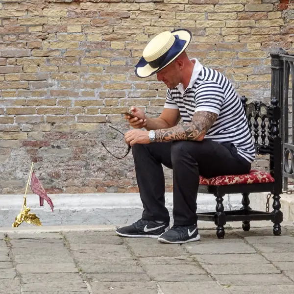 A gondolier checks his phone while awaiting customers in Venice, Italy.